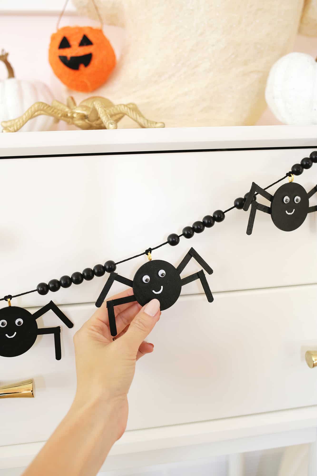 wooden spider garland strung across a console table decorated with pumpkins