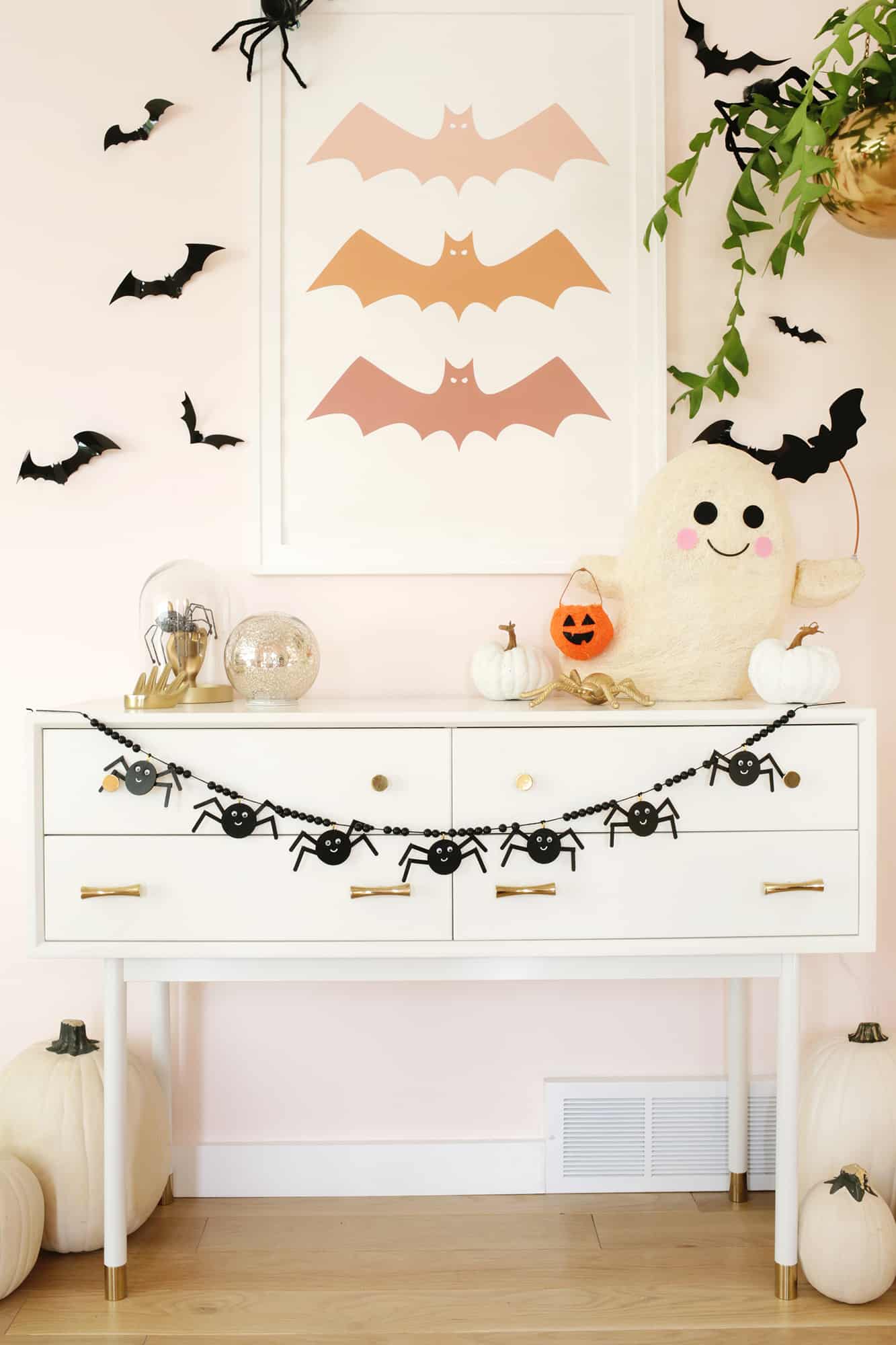 wooden spider garland strung across a console table decorated with pumpkins